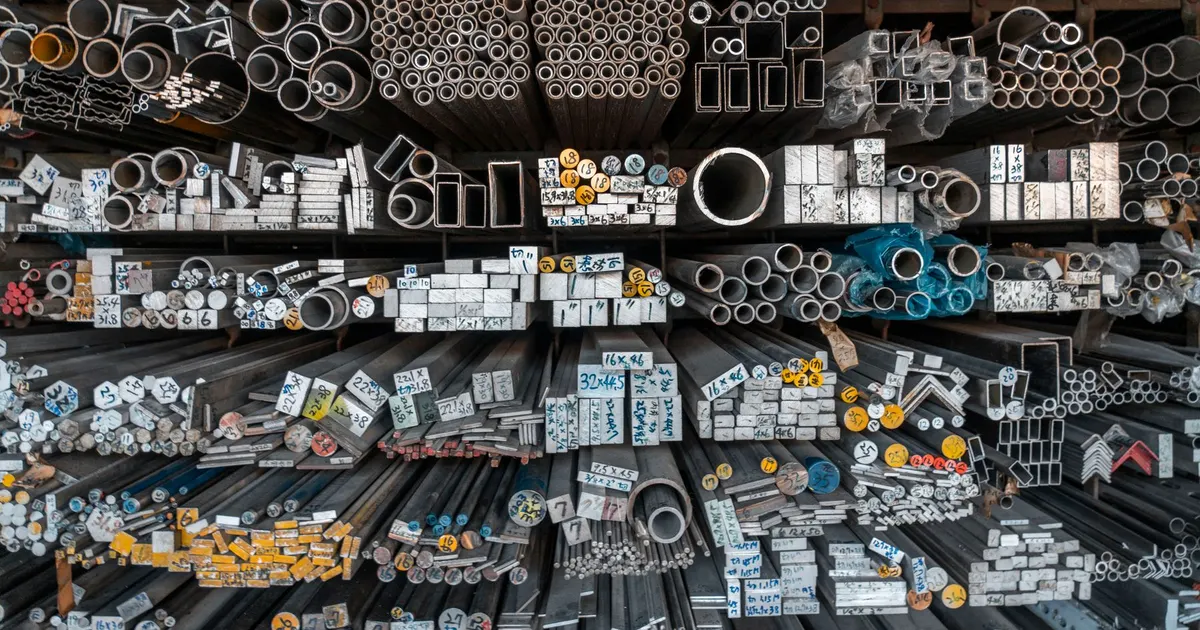 Racks of steel tube and bar stock at a metal supplier, the kind of stock that 4130 vs 4140 chromoly parts are cut from